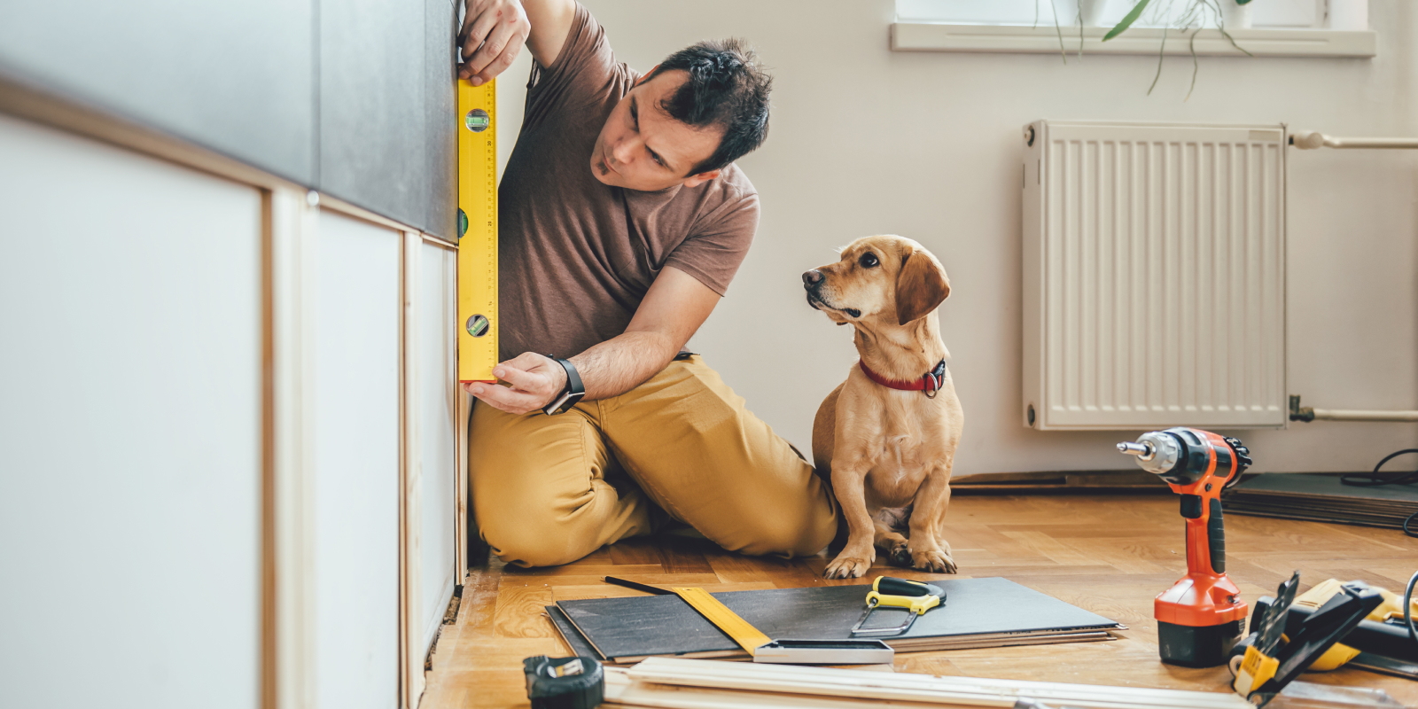 Un perro al lado de un contratista haciendo renovaciones a un hogar.