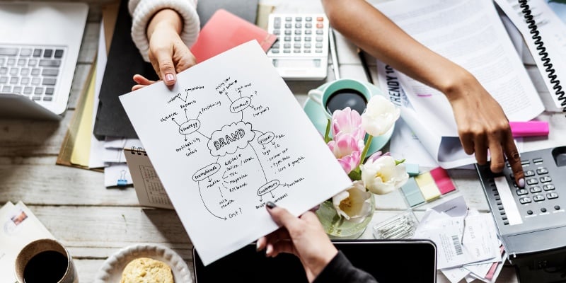 imagen de una mano entregandole una explicacion de marca a otra persona. 