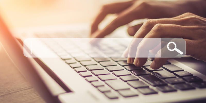 Barra de busqueda con una computadora en el fondo.