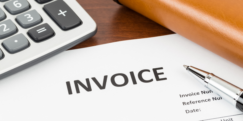 Invoice, calculator, and pen on a desk. 