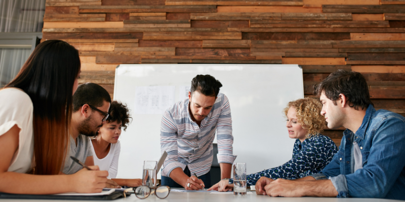 Equipo al rededor de una mesa construyendo un plan de accion.