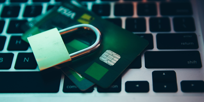 Un candado y una tarjeta de credito sobre las teclas de una computadora.